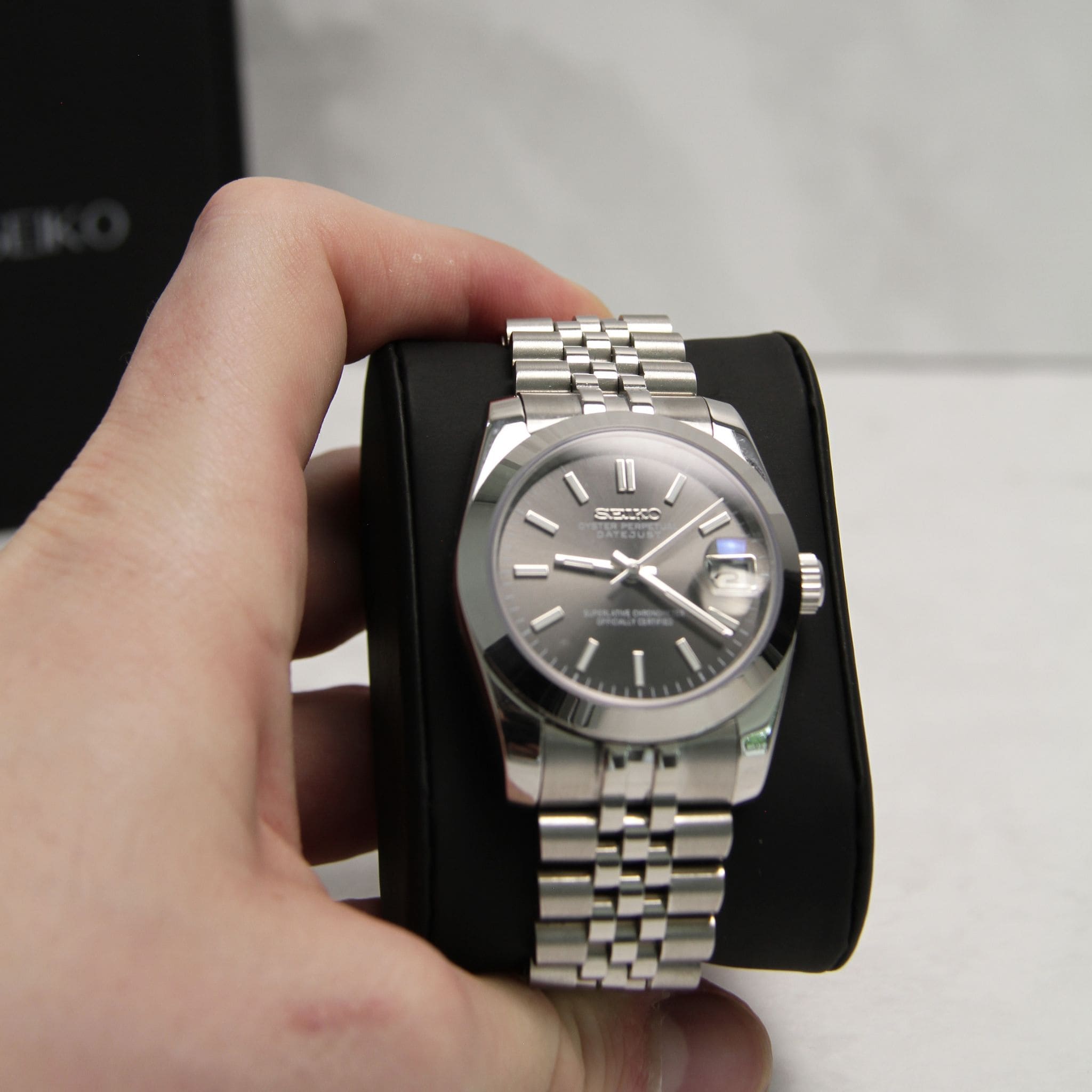 Montre Seiko mod datejust gris 36mm vu de face sur coussin