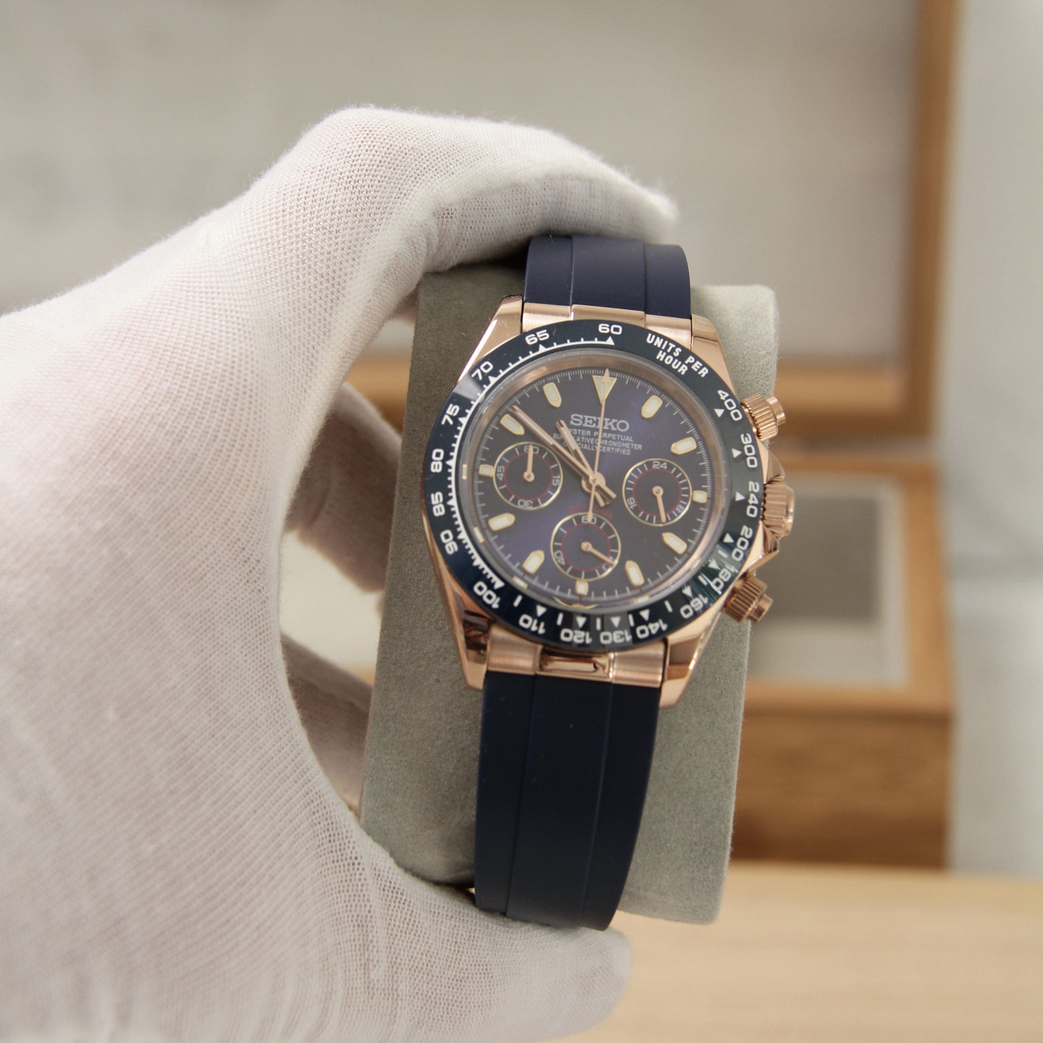 Montre Seiko mod daytona or rose bleu vu de face sur coussin.