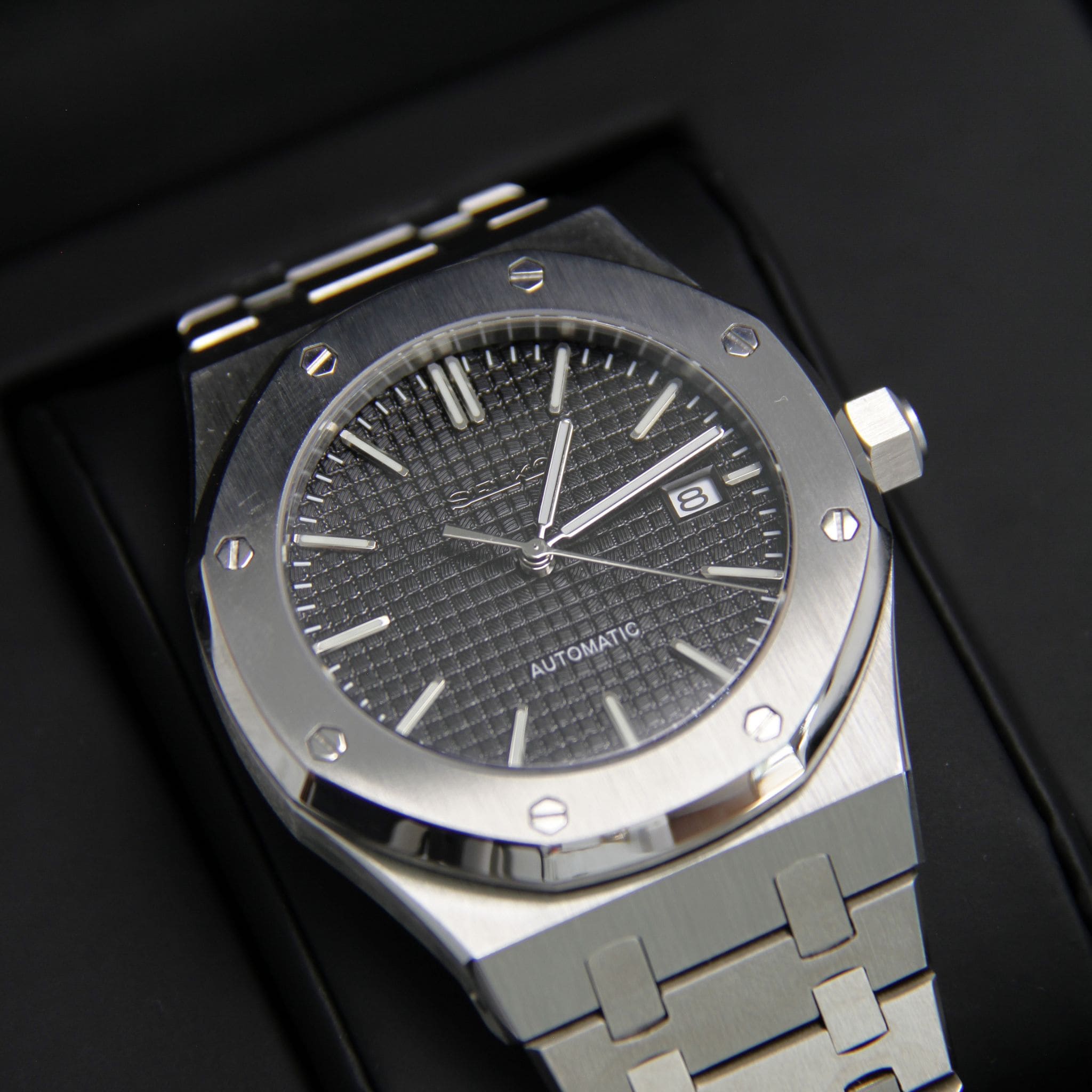 Montre Seiko mod royal oak noir vu de face sur coussin.