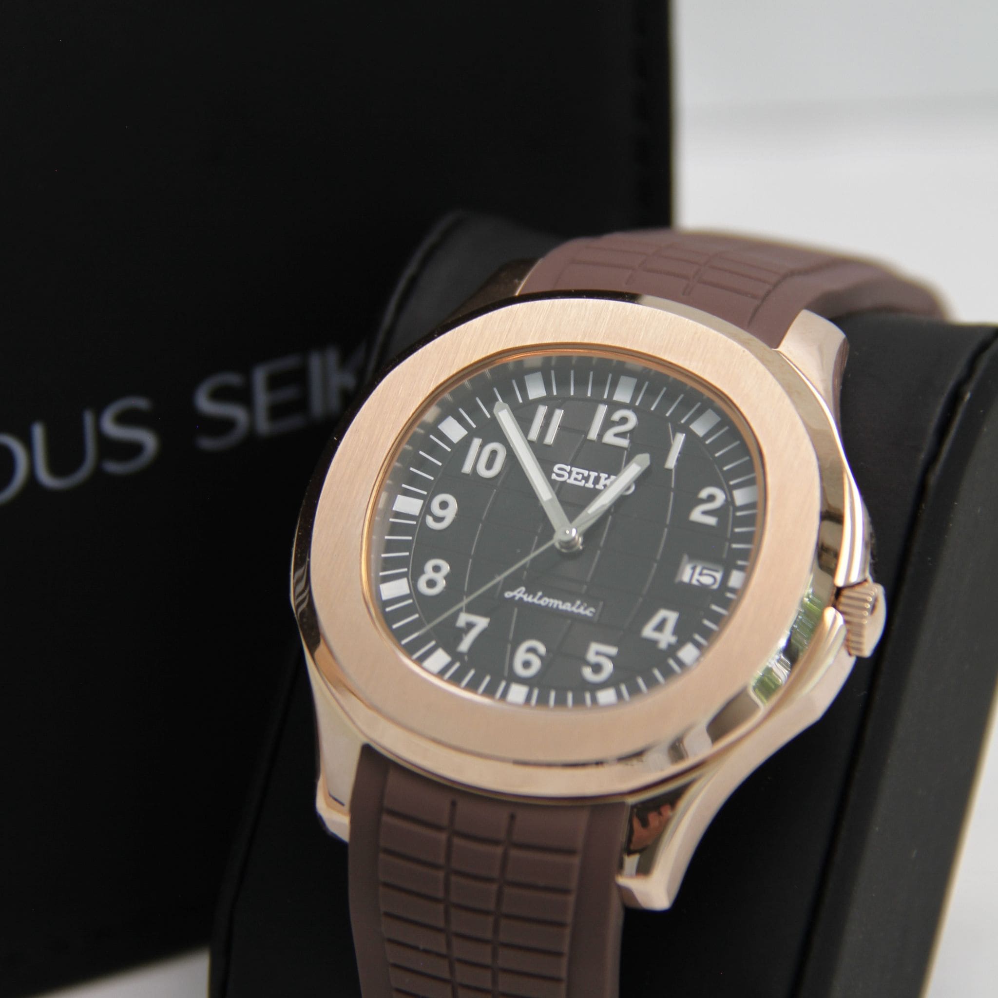Montre Seiko mod aquanaut or rose noir vu de face sur coussin.