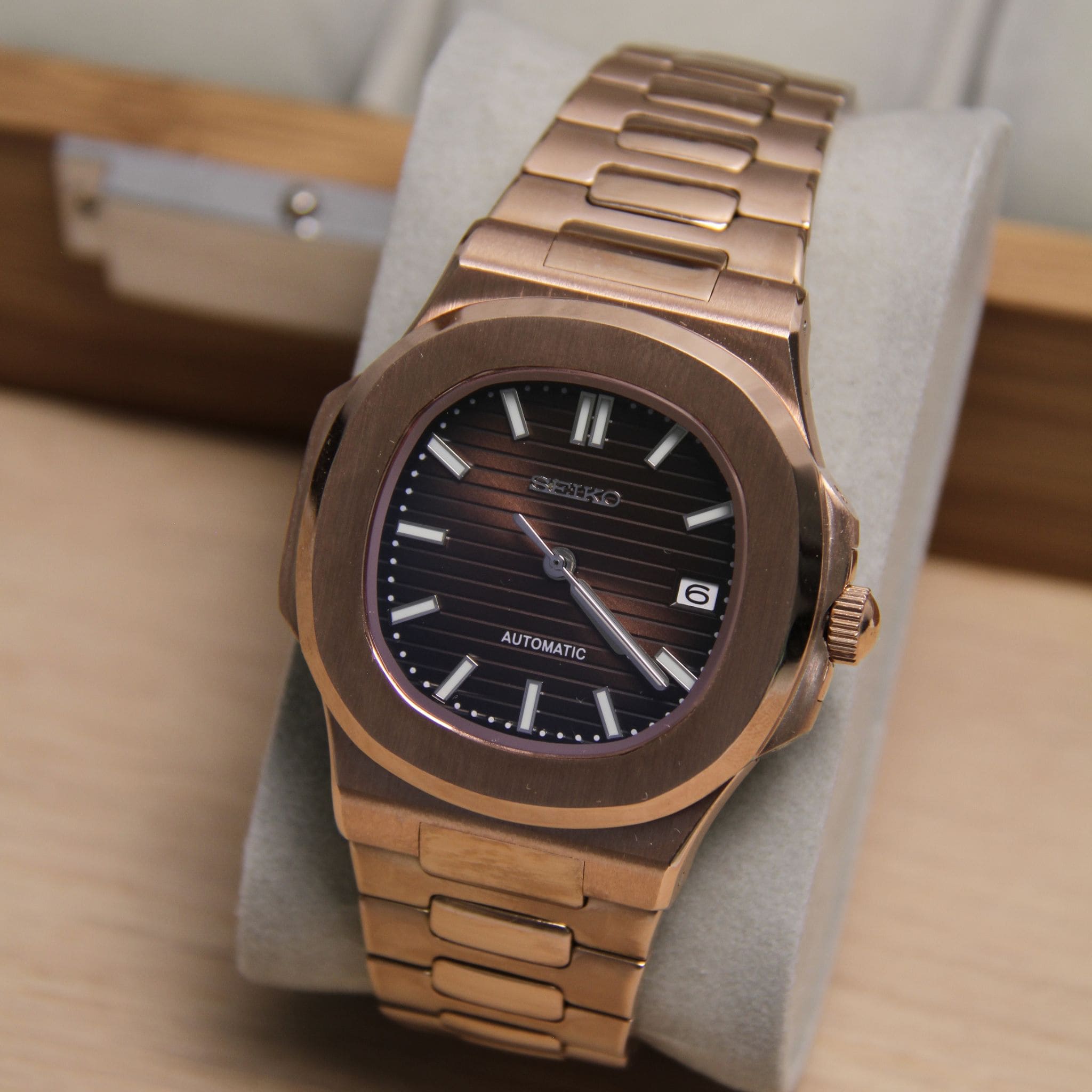 Montre Seiko mod nautilus marron or rose vu de face sur coussin. 